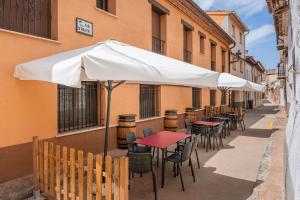 a row of tables and chairs under an umbrella on a sidewalk at Hotel El Horno in La Puebla de Valverde