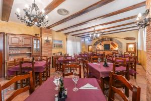 a restaurant with purple tables and chairs in a room at Hotel El Horno in La Puebla de Valverde