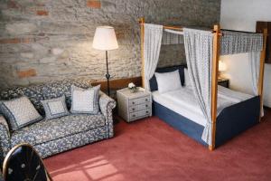 a bedroom with a canopy bed and a couch at Hotel guter Hirte in Huttwil