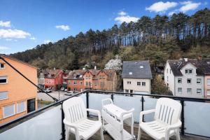 a balcony with white chairs and a view of a city at Loft Nagoldtal in Pforzheim