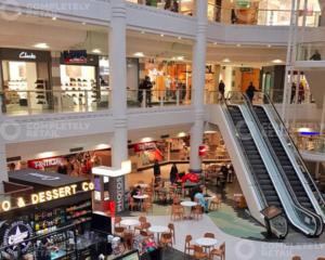 a shopping mall with an escalator and people in it at New,London Hideaway Studio in Woking