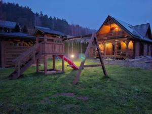 a playground with a slide in front of a cabin at Dom u Julii Bieszczady in Ustrzyki Dolne