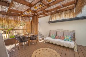 a porch with a couch and a table on a deck at Ô Bel Appart, piscine privée & BBQ, ambiance balinaise in Les Cocos