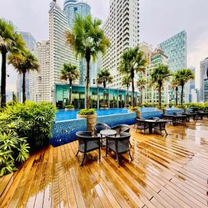 a restaurant with tables and palm trees in a city at Vortex by klcc view in Kuala Lumpur