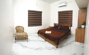 a bedroom with a bed and a chair at Sandora Home Stay in Varkala