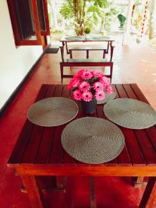 a wooden table with three tables and flowers on it at Canal Resort Udawalawa in Ratkarawwa