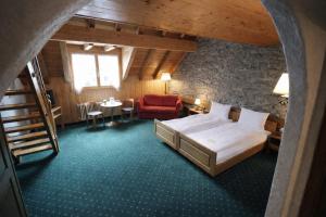 a bedroom with a bed and a chair and a table at Hotel guter Hirte in Huttwil