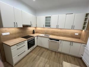 an empty kitchen with white cabinets and a sink at Apartmán REBEKA in Holíč