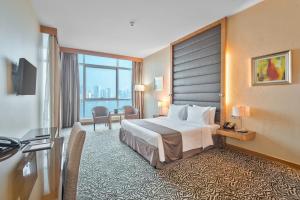 a hotel room with a bed and a large window at Copthorne Hotel Sharjah in Sharjah