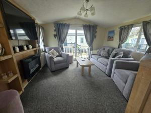 a living room with two couches and a tv at Lapwing 26 in Scratby