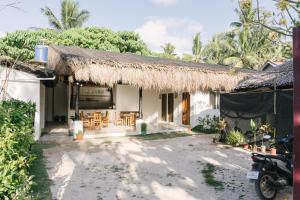 a house with a thatched roof and a patio at Villa Gumamela Siargao in Catangnan