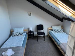 ein Zimmer mit zwei Betten und einem Stuhl in der Unterkunft MECHELinn in Mechelinki