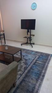 a living room with a flat screen tv and a couch at Private Rooms For Rent Near Airport - Raha Hostel in Ḩayl Āl ‘Umayr
