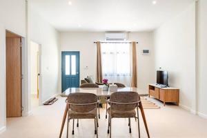 ein Wohnzimmer mit Tisch, Stühlen und Fernseher in der Unterkunft Chambers in Phuket