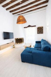 a living room with a blue couch and a tv at SeaScapeHome Serifos in Serifos Chora