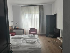 a hotel room with two beds and a chair at La Romică in Mediaş