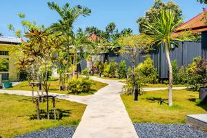 ein Gehweg durch einen Garten mit Palmen in der Unterkunft Chambers in Phuket