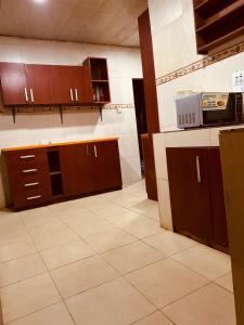 an empty kitchen with brown cabinets and a microwave at Executive 2BR at Redemption Camp in Loburo