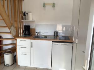 a small kitchen with white cabinets and a sink at Penty in Crozon +5 photos