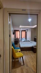 a hotel room with two beds and a yellow chair at Merkez Otel in İzmir