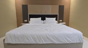 a large white bed with white sheets and pillows at Hotel Tian in Nabire