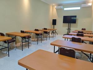 an empty classroom with tables and chairs and a tv at Hotel Tian in Nabire +1 photo