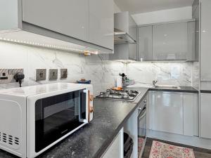 a white kitchen with a microwave and a stove at Bletchley Retreat in Bletchley +26 photos