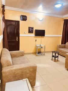 a living room with a couch and a tv at Executive 2BR at Redemption Camp in Loburo