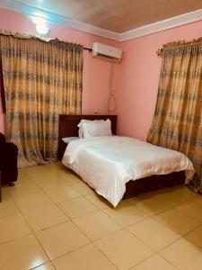 a bedroom with a bed with white sheets and pink walls at Executive 2BR at Redemption Camp in Loburo