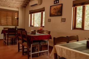 a dining room with a table and chairs and windows at Wild Woods Tiger Resort in Nagpur