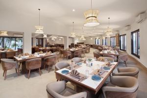 a restaurant with wooden tables and chairs and windows at Treat Resort Rajkot in Rajkot