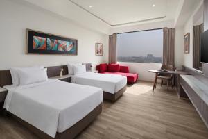 a hotel room with two beds and a red chair at Treat Resort Rajkot in Rajkot +12 photos