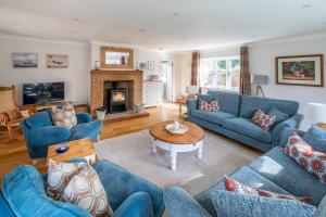a living room with blue couches and a fireplace at Waterside in Wiveton
