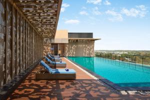 a pool with blue lounge chairs on the side of a building at Hyatt Place Bhopal in Bhopal