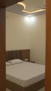 a bedroom with a white bed with a light on the ceiling at Hotel KK Place in Chittaurgarh