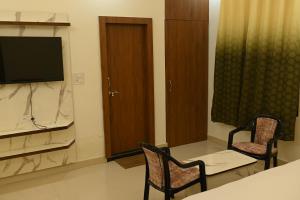 a living room with two chairs and a television at Hotel KK Place in Chittaurgarh