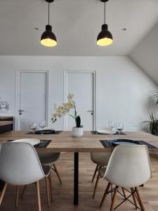 a dining room with a wooden table and white chairs at O'Phare Ouest in Plouguerneau