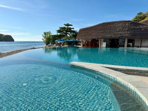 a swimming pool next to the ocean with a building at Komodo Resort in Sebayur