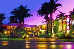 a building with palm trees in front of it at Sapphire Waters Motor Inn in Merimbula