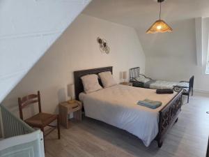 a bedroom with a large bed and a chair at Maison Bretagne Authentique in Plémy