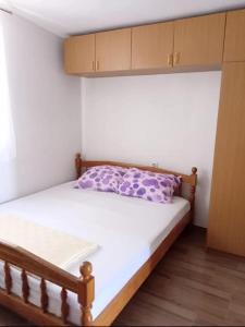 a small bedroom with a bed with a purple pillow at Apartmani Marija Rtina in Rtina