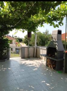a grill sitting on a patio under a tree at Apartmani Marija Rtina in Rtina +5 photos
