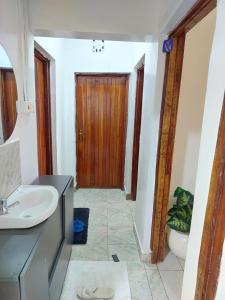 a bathroom with a sink and a wooden door at JJHomes in Eldoret