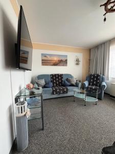 a living room with a blue couch and a tv at Studio Heimi I mit Balkon strandnah Cuxhaven-Grimmershörnerbucht in Cuxhaven