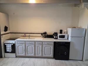 a kitchen with a white refrigerator and a dishwasher at Maison Bretagne Authentique in Plémy