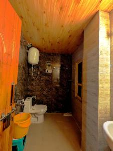 a bathroom with a toilet and a stone wall at Misfits Hostel and Cafe in Shoja