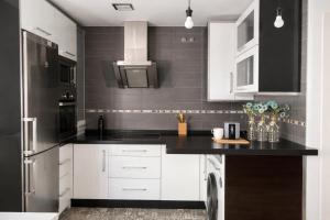 a kitchen with white cabinets and black counter tops at ático con terraza- solarium in Écija