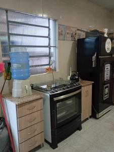eine Küche mit schwarzem Herd und Kühlschrank in der Unterkunft Quarto suíte 2 in Itaqui