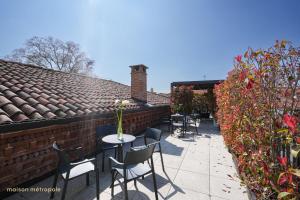 a patio with tables and chairs and a brick wall at Palazzo Zoya - Elegant Historic Suites - Asti Center - Near Langhe & Monferrato in Asti