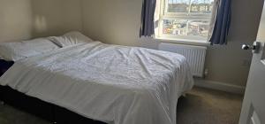 a bedroom with a bed with a white comforter and a window at Private room in a 2-bedroom house in Dinnington